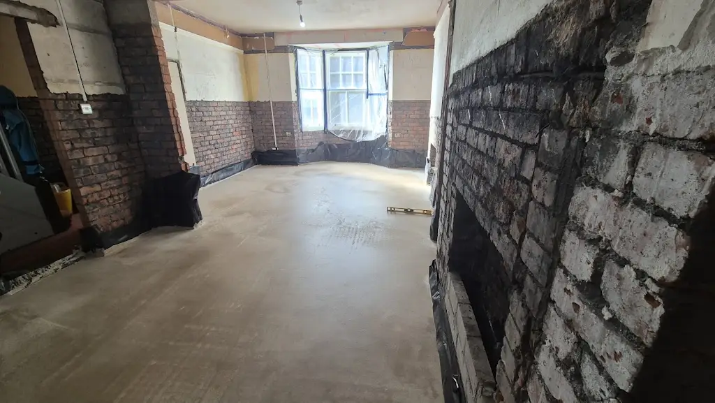 A newly laid floor surface in the bay-window room, with walls still awaiting reinstatement.
