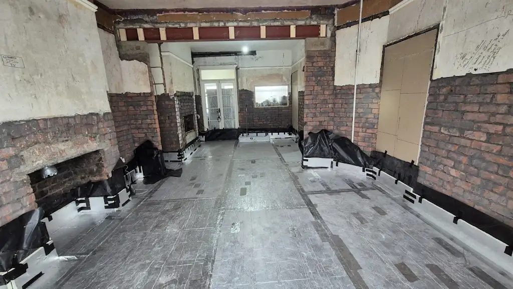 Opened fireplace and a view towards the rear through connected rooms during renovation work.