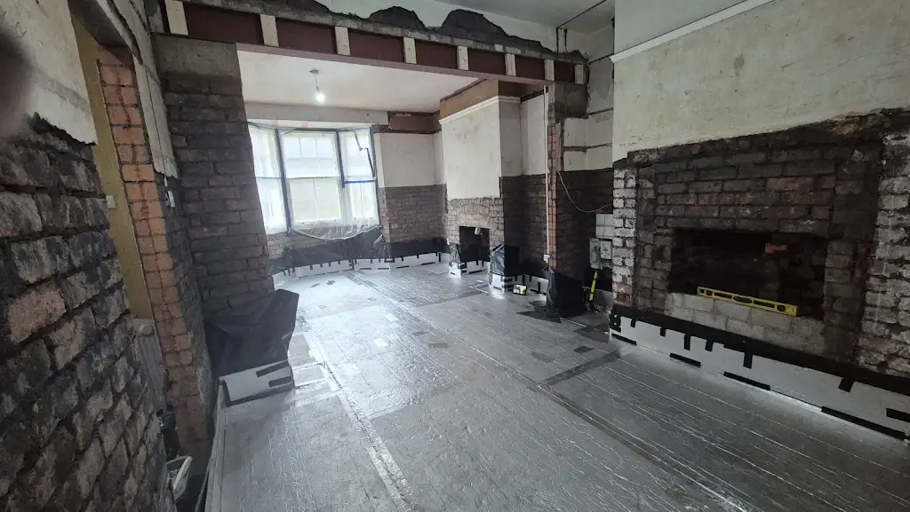 Fireplace opening and chimney breast prepared during renovation, with floor insulation fitted around it.