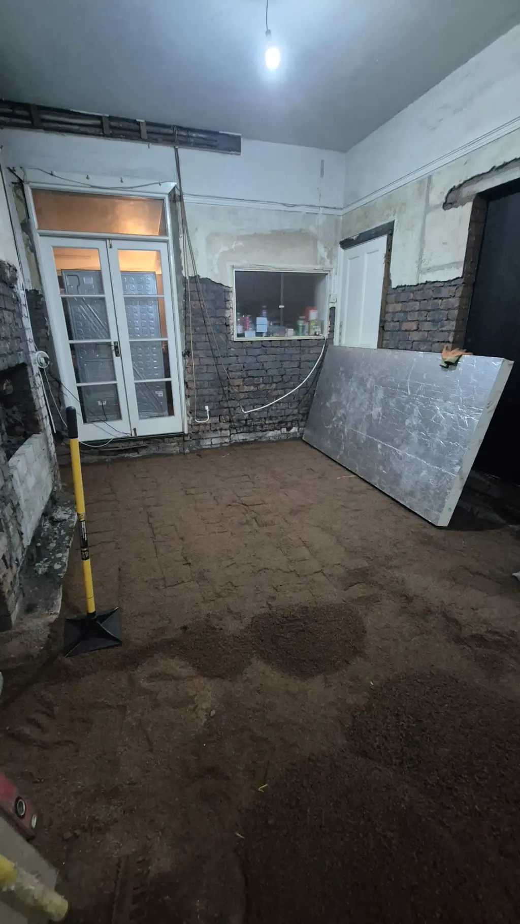 Stripped walls and a prepared floor base in the rear room, before floor insulation is fitted.