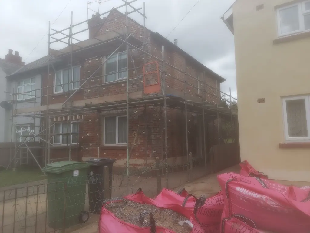 Wide view of scaffolded brick property during wall-tie replacement